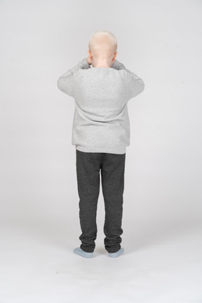 Back view of boy rubbing his eyes