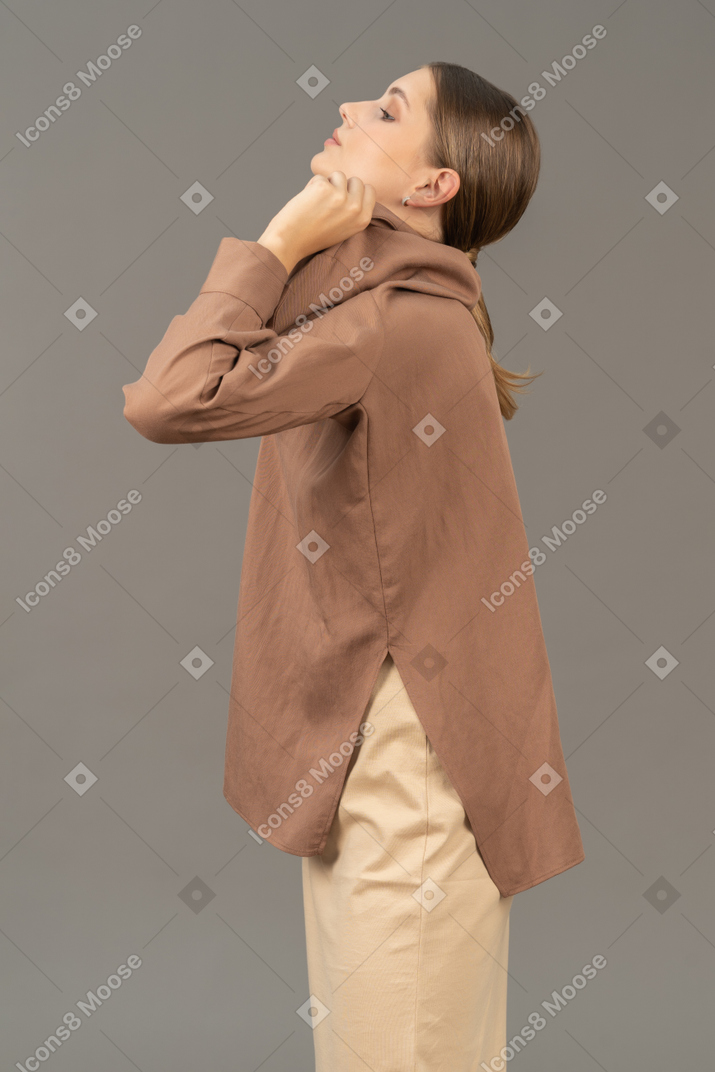 Side view of a young woman pulling her shirt over the head