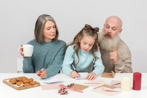 Kind mädchen unterzeichnet karte und opa sagt ihr, was sie schreiben soll