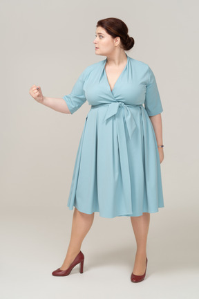 Front view of a woman in blue dress showing fist