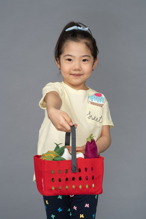 Portrait of a little girl holding out a shopping basket