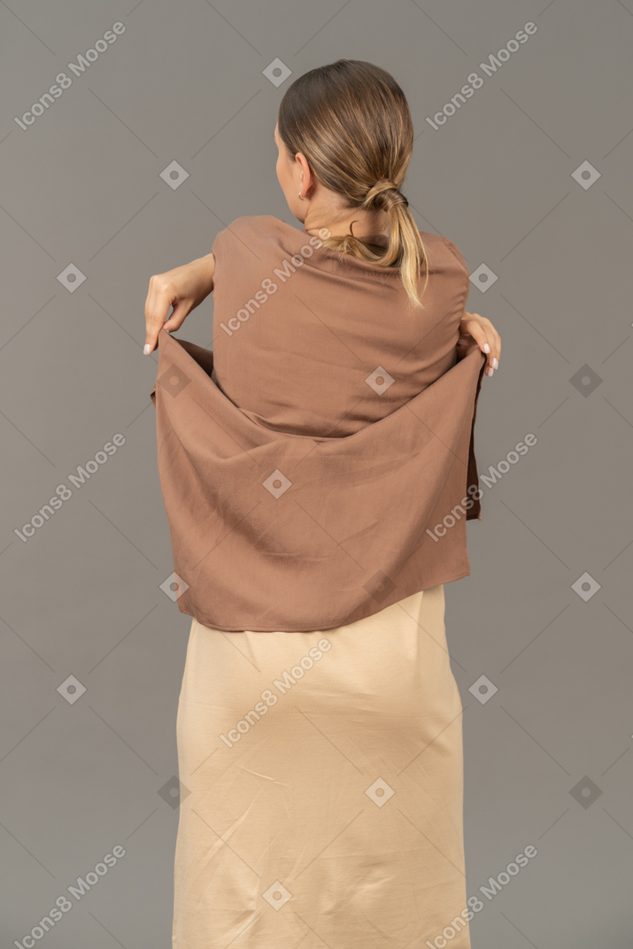 Back view of a woman taking her shirt off with crossed hands