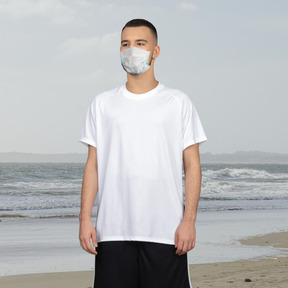 A man standing on a beach wearing a face mask