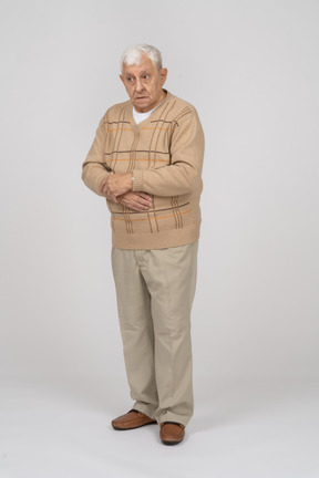 Vue de face d'un vieil homme en vêtements décontractés regardant quelque chose avec intérêt