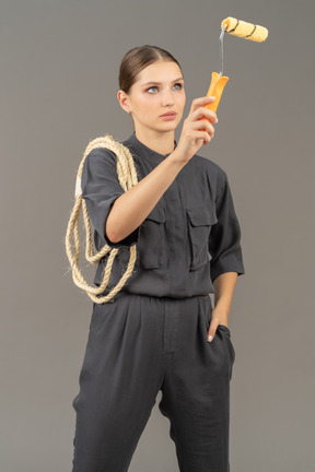 Woman in gray coveralls using a paint roller