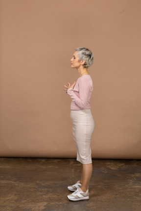 Vista lateral de uma mulher com roupas casuais, posando com as mãos no peito