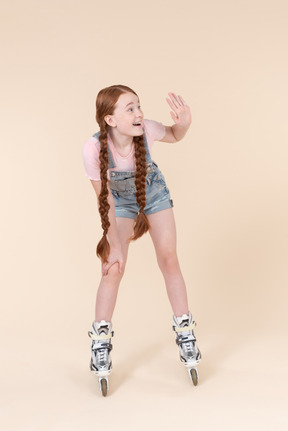 Teenager kid girl standing on roller skates and waving with a hand