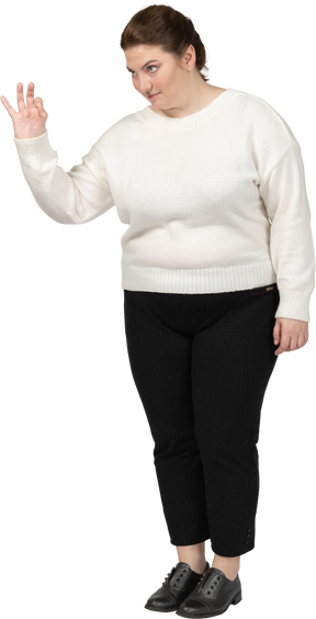 Okサインを示す白いセーターのプラスサイズの女性
