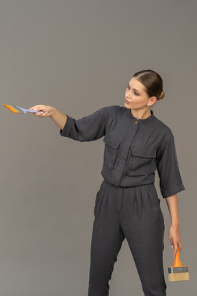 Frau in grauen overalls posiert mit pinseln