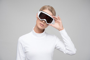 Young blonde woman adjusting ski goggles