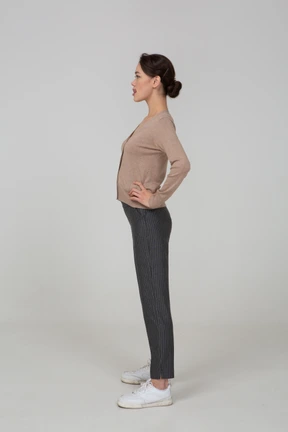 Side view of a young lady in pullover and pants putting hands on hips