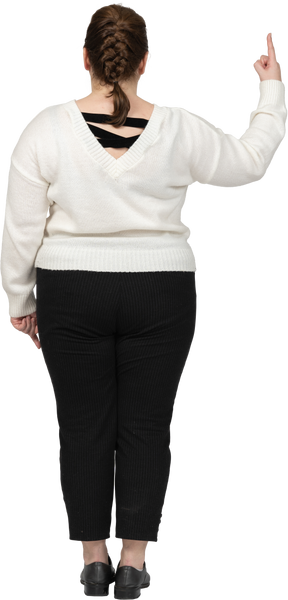 Plus size woman in casual clothes pointing up with a finger