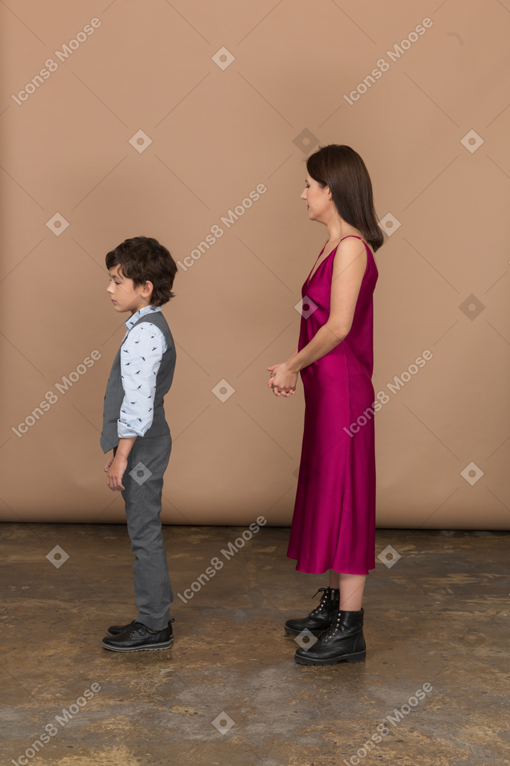 Jovem mulher com vestido vermelho e menino parado