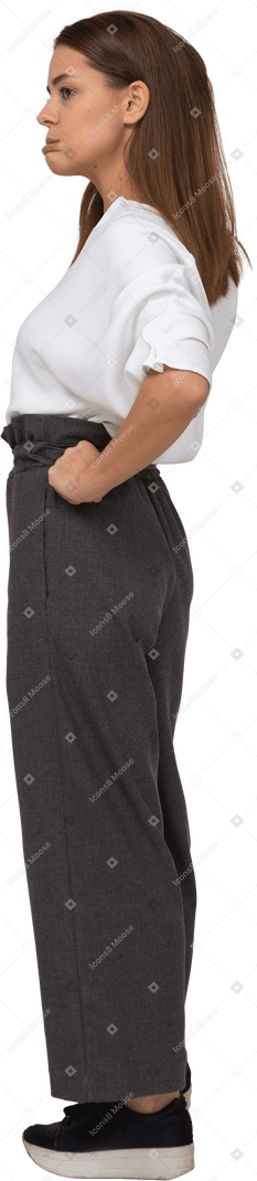 Vista lateral de una joven disgustada en ropa de oficina poniendo las manos en las caderas