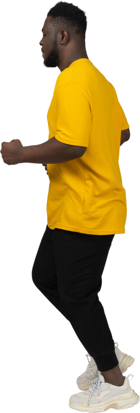 Side view of a running young dark-skinned man in yellow t-shirt
