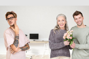 Jeune homme et femme âgée tenant un bouquet et un autre homme à côté d'eux regardant de côté