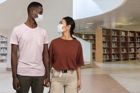 A man and a woman wearing masks in a library