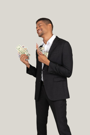 Three-quarter view of a smiling young man in black suit holding banknotes