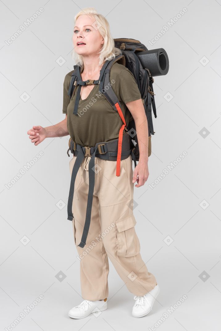 Mature female tourist carrying heavy backpack and kind of gasping