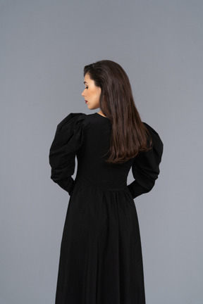 Back view of a young lady in a black dress holding hands together