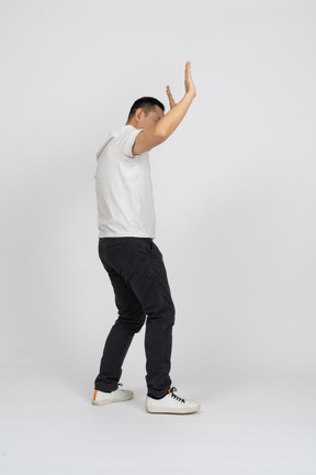 Side view of a man in casual clothes standing with raised arms