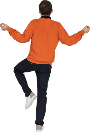 オレンジ色のスウェットシャツのポーズで若い男
