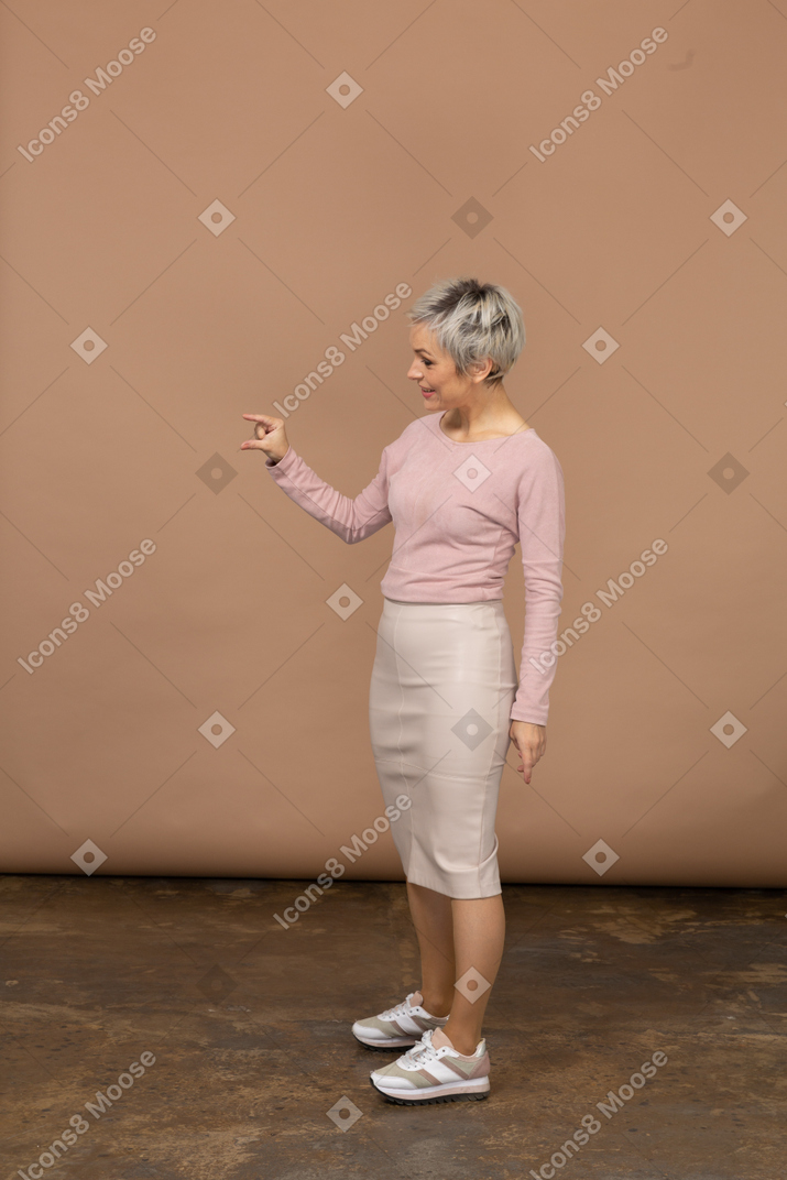 Vista lateral de uma mulher feliz em roupas casuais mostrando o tamanho pequeno de algo