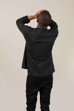 Back view of young man with hands on head