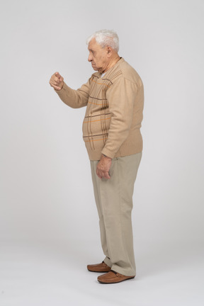 Side view of an old man in casual clothes pointing with finger