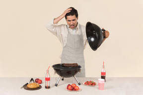 Jadeando joven hombre caucásico preparando una barbacoa