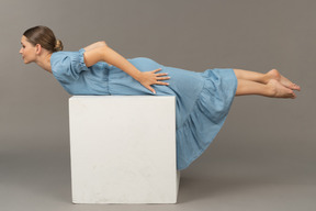 Vista laterale della giovane donna sdraiata sul cubo