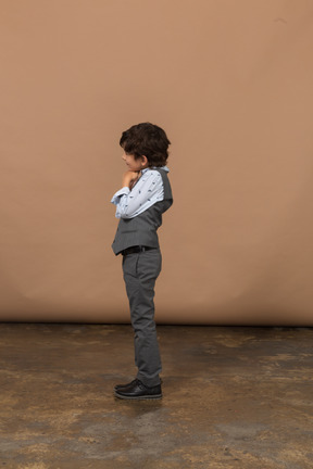 Vista lateral de un chico lindo en traje gris