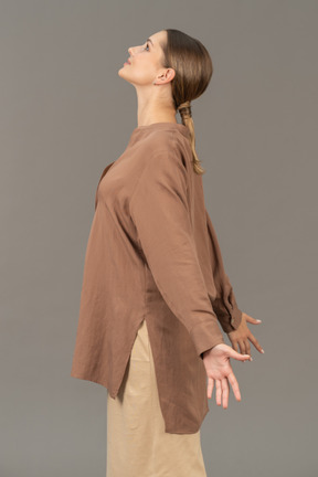 Vista lateral de una mujer mirando hacia arriba con los brazos abiertos