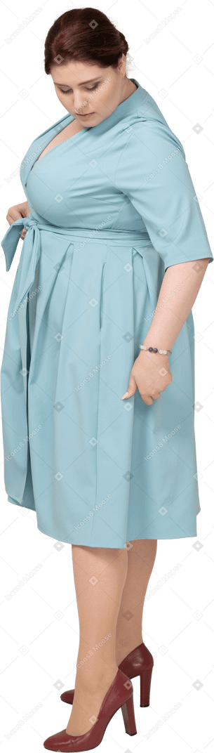 Вид сбоку женщины в синем платье позирует