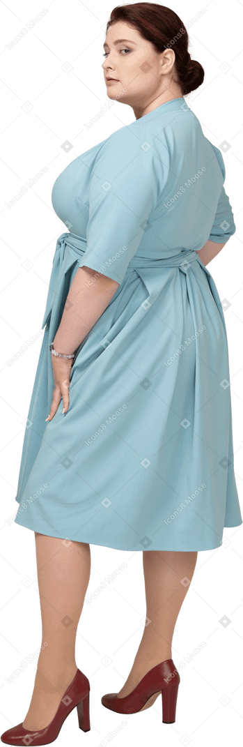 Женщина в синем платье стоит в профиль