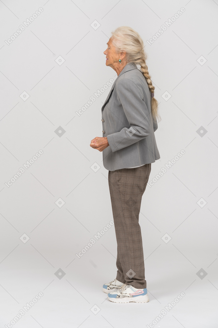 Vista laterale di una donna anziana arrabbiata in tuta che mostra pugno