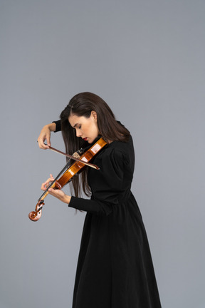 Close-up de uma jovem de vestido preto tocando violino