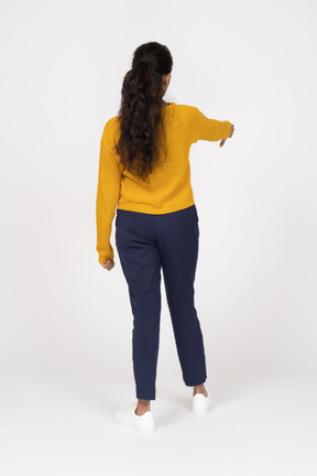 Vista traseira de uma garota com roupas casuais mostrando o polegar para baixo
