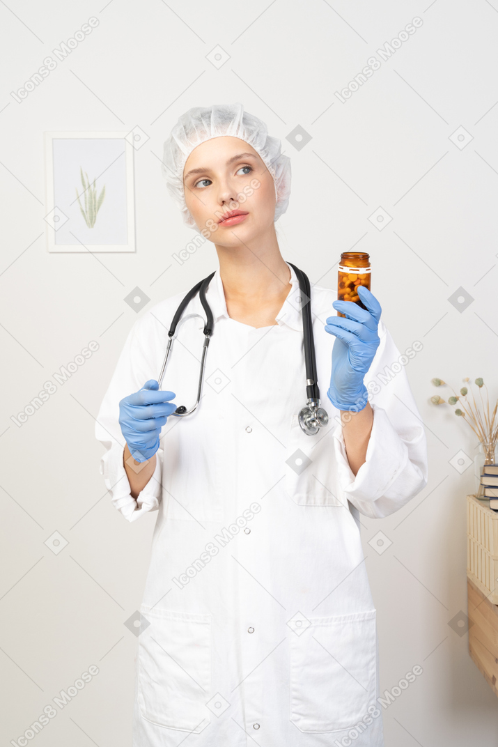 Vista frontale di una giovane dottoressa che tiene un barattolo di pillole of