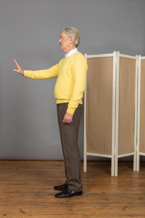 Side view of an old man raising hand