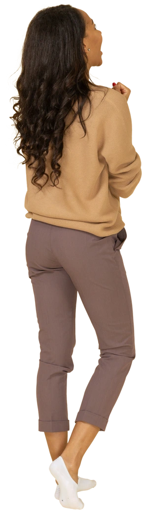 Three-quarter back view of a delighted dark-skinned young female clenching fists