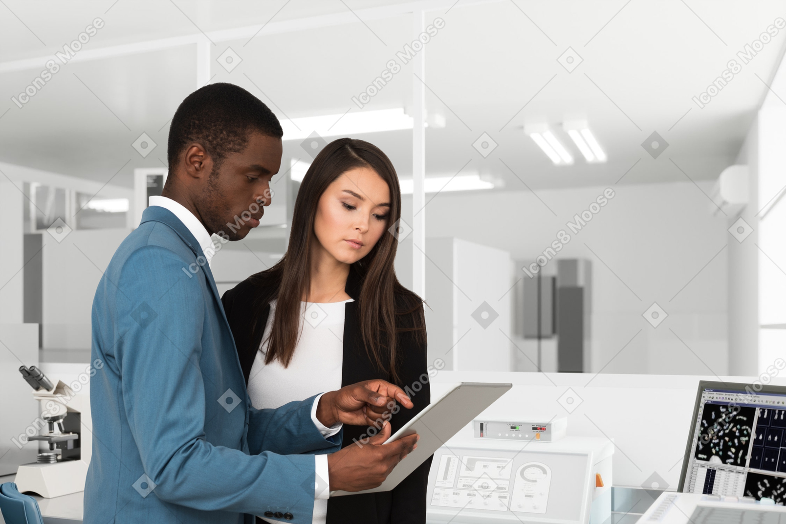 Two young people standing in a medical laboratory and using a tablet