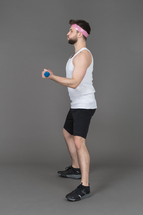 Sporty young man working out biceps muscle in profile