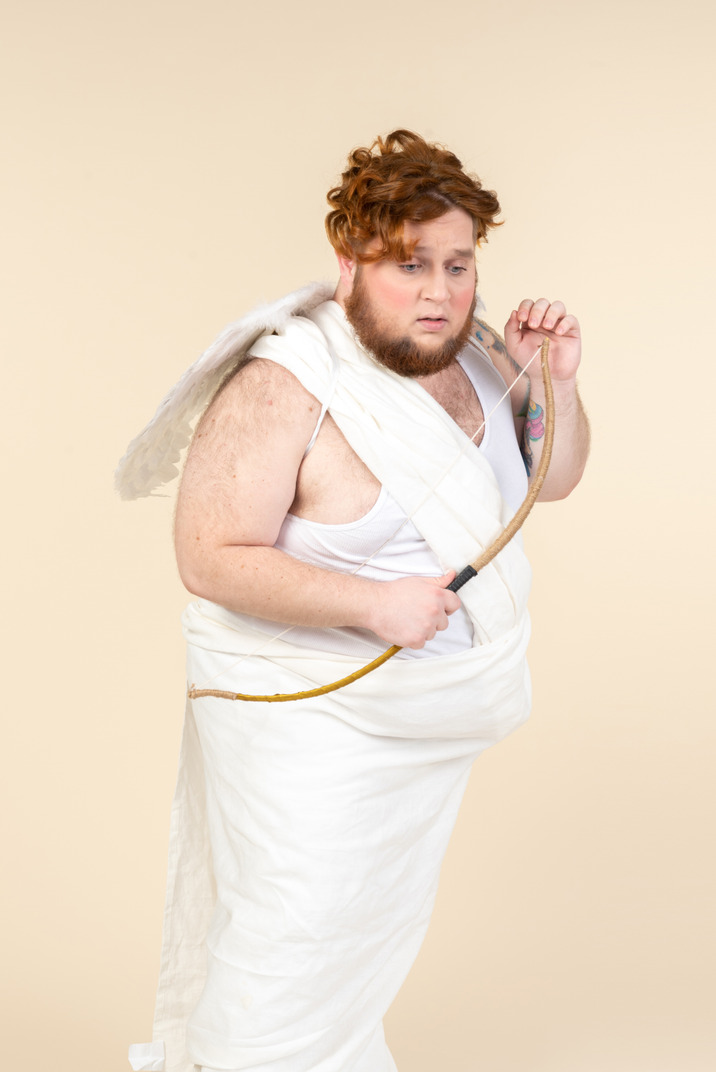 Worried big guy dressed as a cupid holding bow and arrow