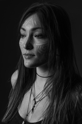 Vista laterale noir foto di una giovane donna con arte del viso che osserva da parte