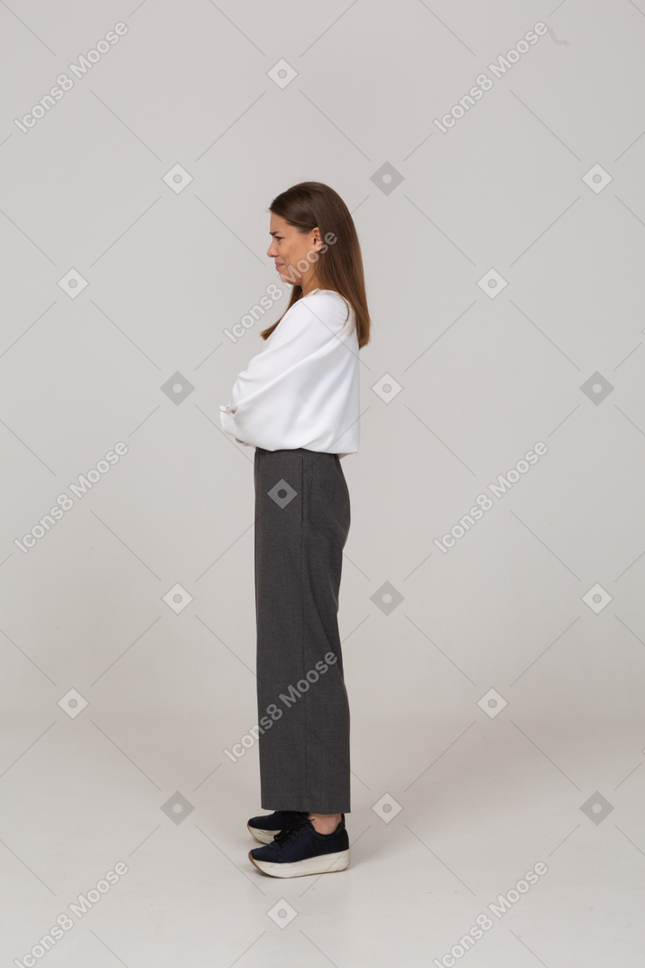 Vista laterale di una giovane donna dispiaciuta in abiti da ufficio che incrociano le braccia