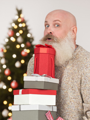 Hombre barbudo con un montón de regalos de navidad