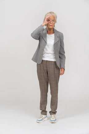 Front view of an old lady in suit looking through fingers