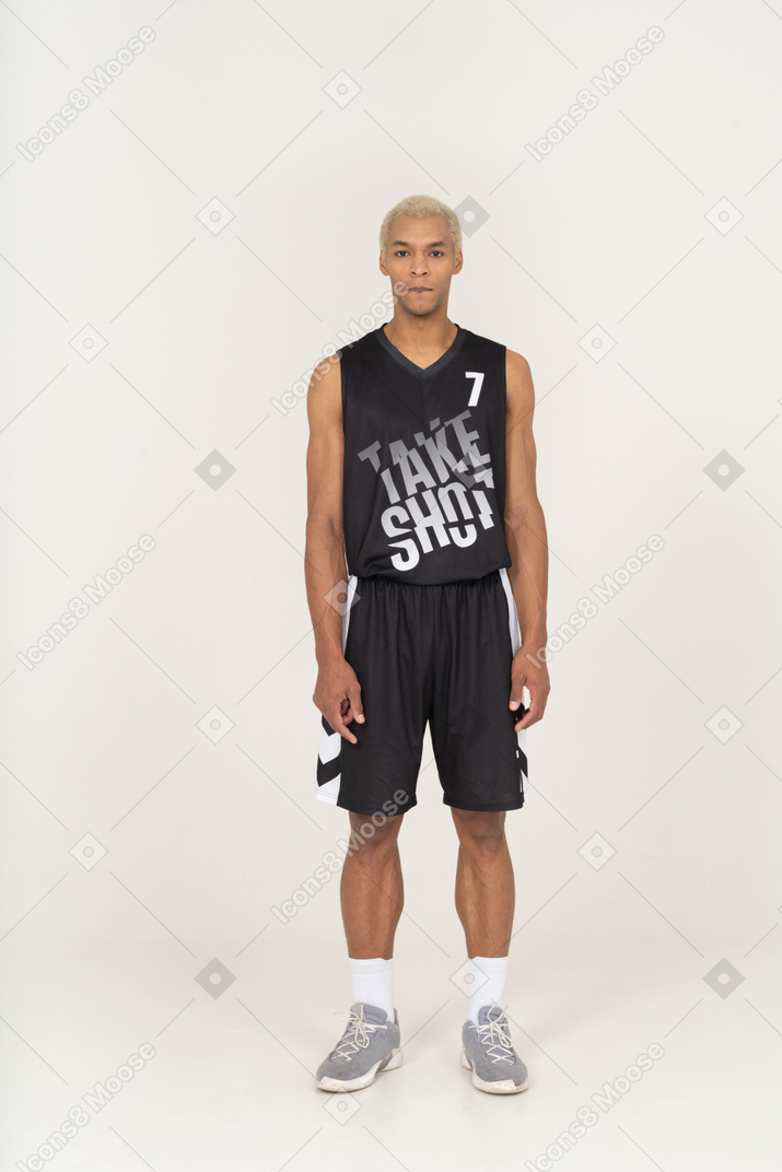 一个年轻的男篮球运动员站着不动咬嘴唇的前视图