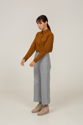 Three-quarter view of a young asian female in breeches and blouse outstretching hands